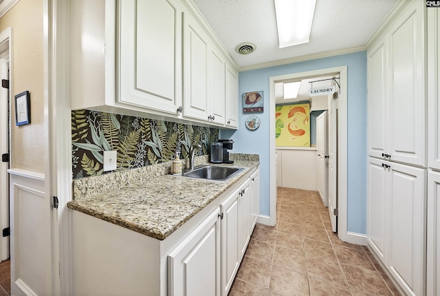 kitchen featuring crown molding, white cabinets, sink, and backsplash