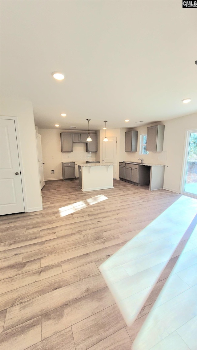 unfurnished living room featuring light wood-type flooring and sink