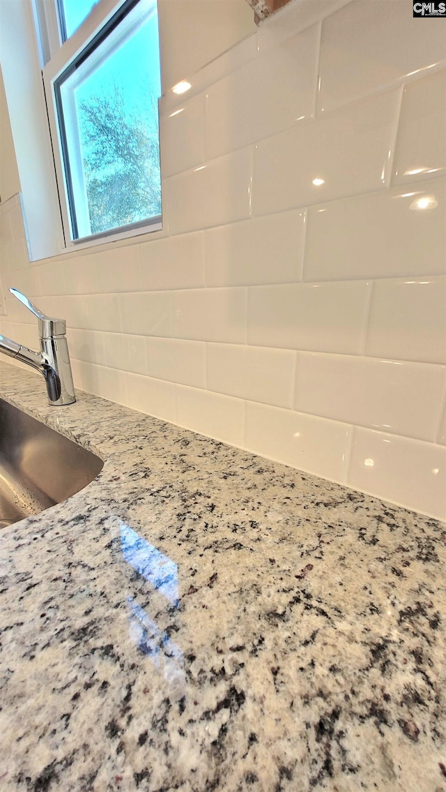 interior details featuring sink, white cabinetry, light stone countertops, and decorative backsplash