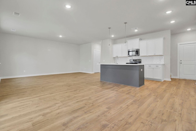 kitchen featuring pendant lighting, light hardwood / wood-style flooring, appliances with stainless steel finishes, an island with sink, and white cabinets