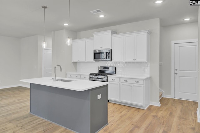 kitchen with sink, decorative light fixtures, white cabinets, and appliances with stainless steel finishes