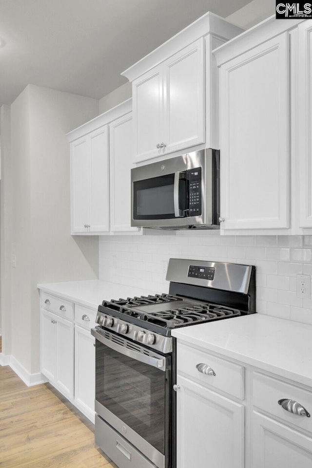 kitchen featuring appliances with stainless steel finishes, light hardwood / wood-style floors, decorative backsplash, and white cabinets