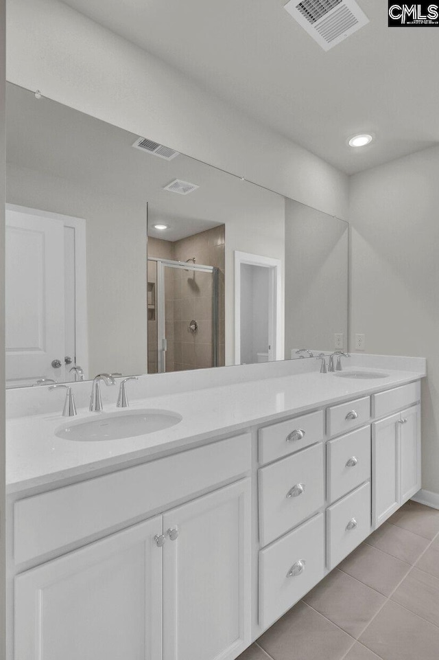 bathroom featuring tile patterned floors, a shower with door, and vanity