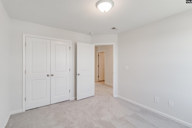 unfurnished bedroom with light carpet and a closet