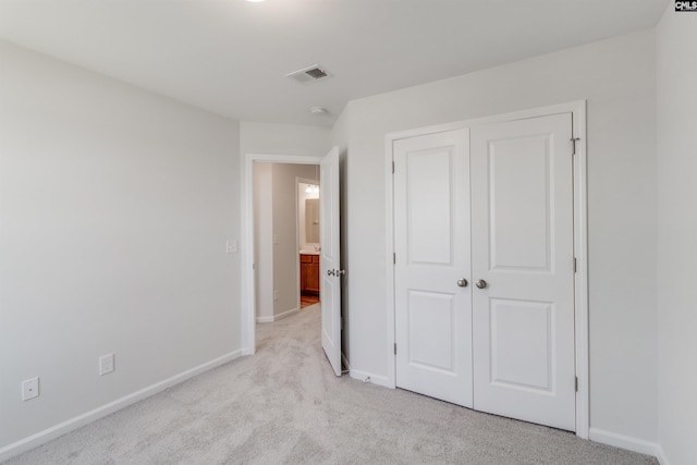 unfurnished bedroom featuring light carpet and a closet