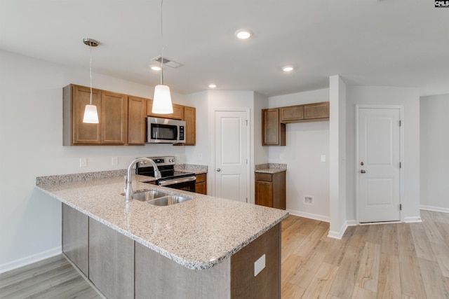 kitchen featuring pendant lighting, sink, stainless steel appliances, kitchen peninsula, and light wood-type flooring