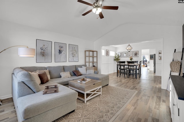 living room featuring hardwood / wood-style flooring, ceiling fan with notable chandelier, and vaulted ceiling