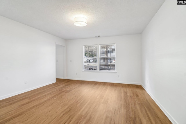 empty room featuring a textured ceiling and light hardwood / wood-style flooring