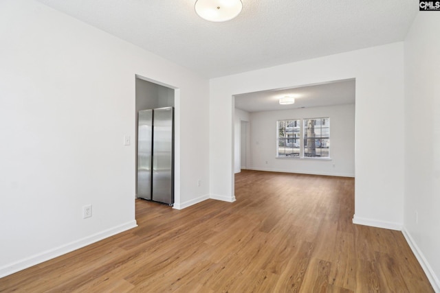 unfurnished room featuring light hardwood / wood-style flooring and a textured ceiling