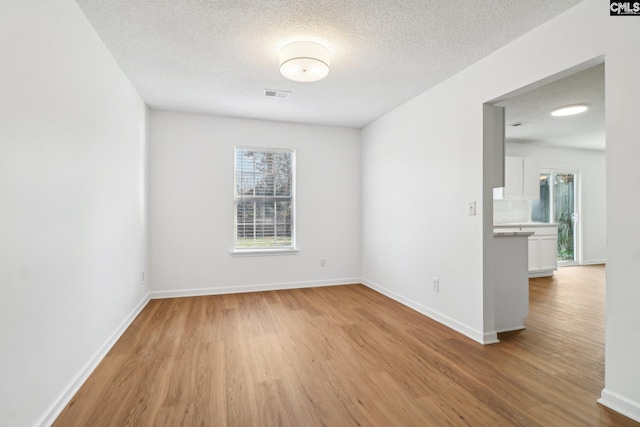 spare room featuring plenty of natural light, light hardwood / wood-style floors, and a textured ceiling