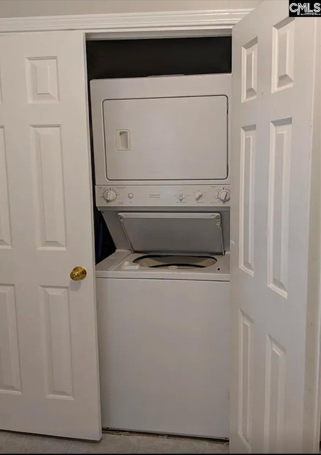 laundry room featuring stacked washer and dryer and light tile patterned floors