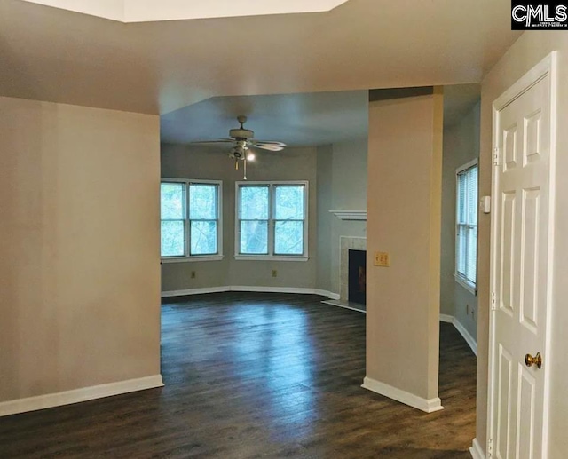 unfurnished living room with a tiled fireplace, ceiling fan, and dark hardwood / wood-style flooring