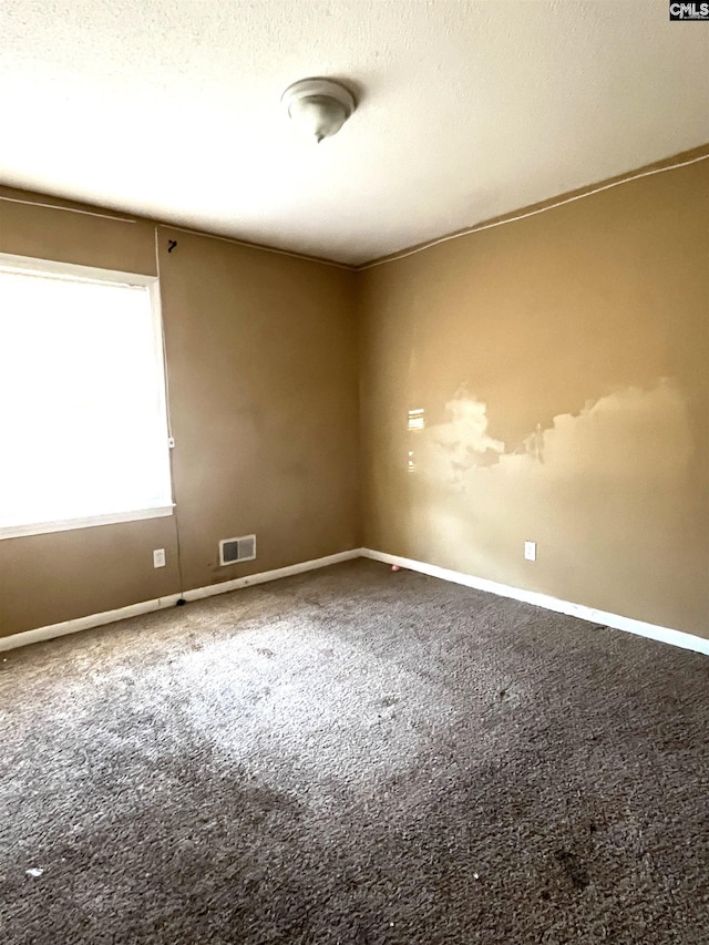 carpeted spare room with a textured ceiling