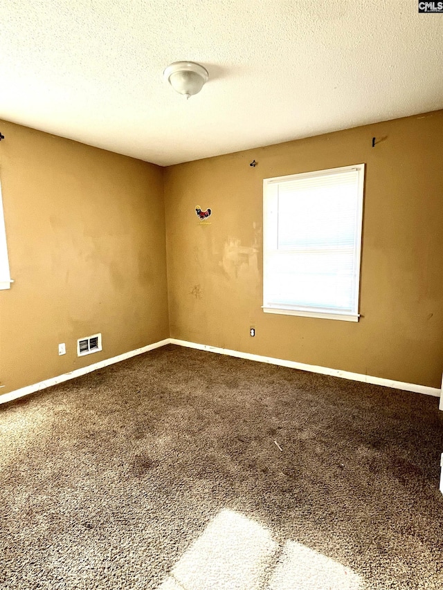 carpeted empty room featuring a textured ceiling