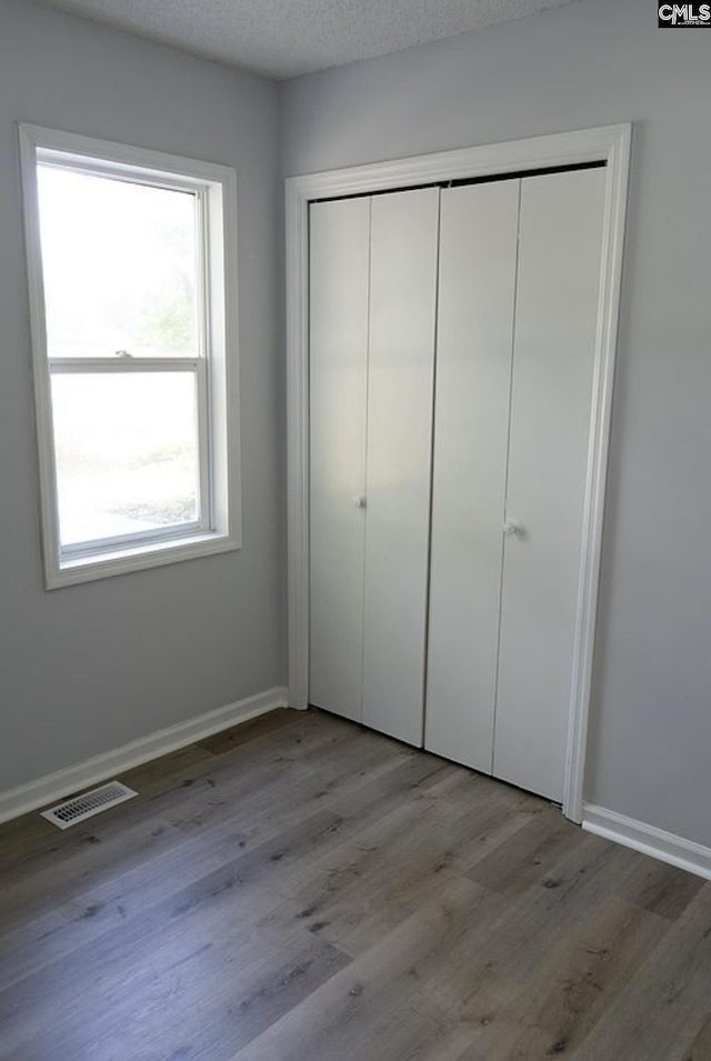 unfurnished bedroom featuring light hardwood / wood-style floors, a closet, and a textured ceiling