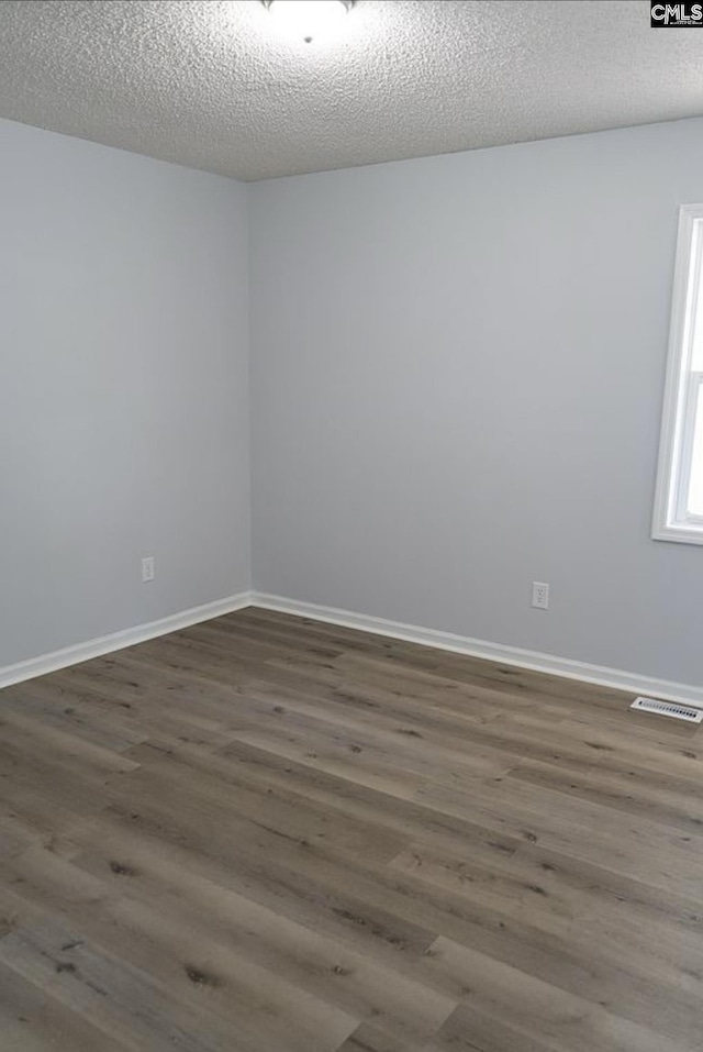 empty room featuring a textured ceiling and dark hardwood / wood-style flooring