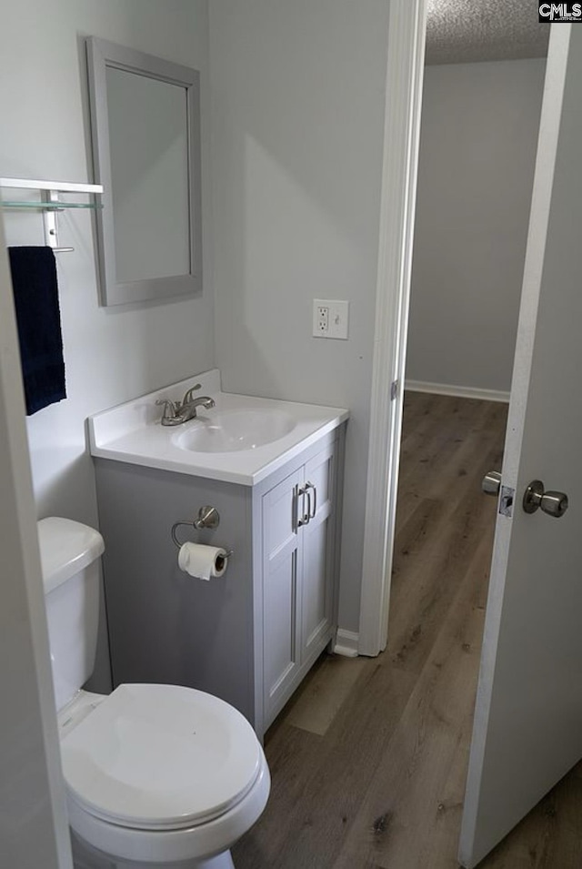 bathroom featuring hardwood / wood-style flooring, vanity, a textured ceiling, and toilet