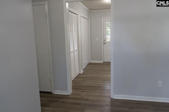 hallway featuring ornamental molding, dark hardwood / wood-style floors, and a textured ceiling