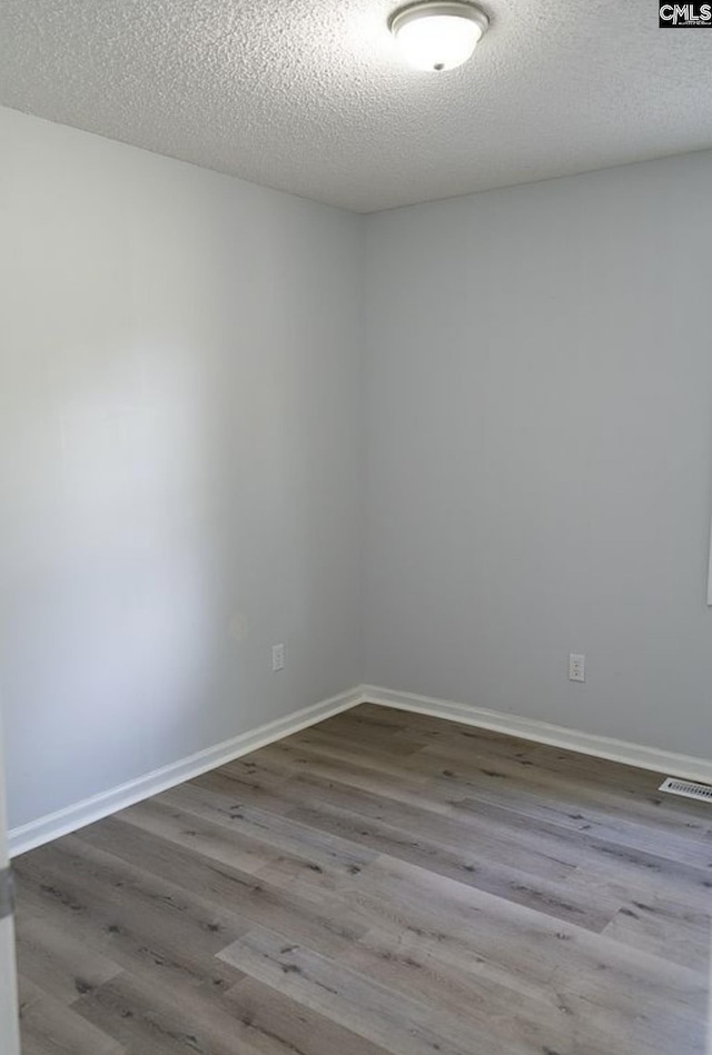 spare room with a textured ceiling and light wood-type flooring