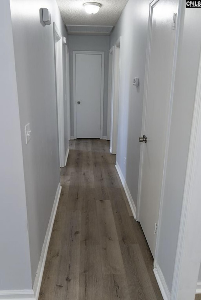 corridor with a textured ceiling and light hardwood / wood-style flooring