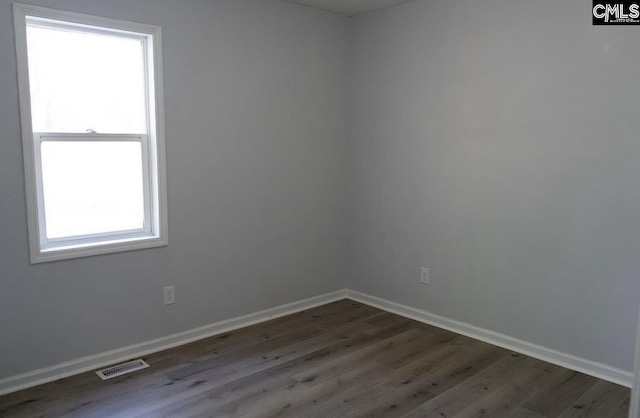 empty room with dark hardwood / wood-style floors and a healthy amount of sunlight