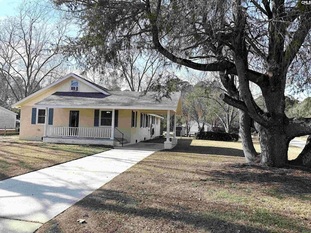 country-style home with covered porch, driveway, a carport, and a front lawn