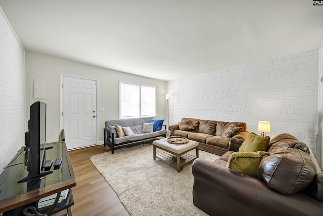 living room featuring wood-type flooring and brick wall