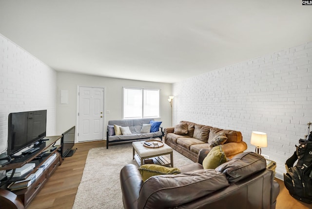 living room featuring brick wall and wood-type flooring