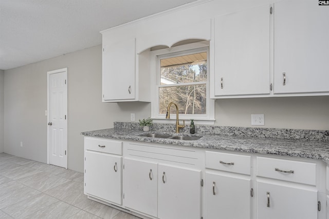 kitchen with sink, white cabinets, and a textured ceiling