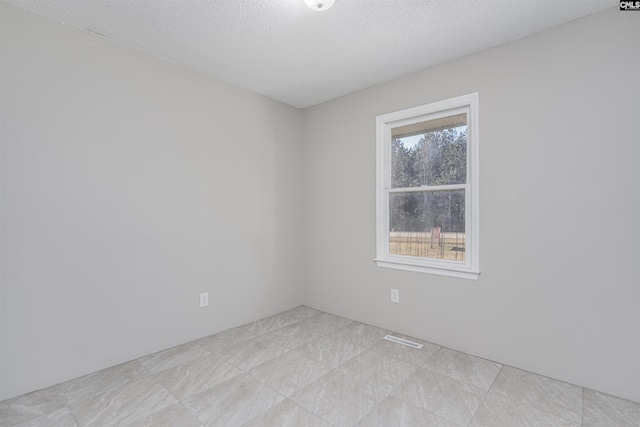 empty room featuring a wealth of natural light and a textured ceiling