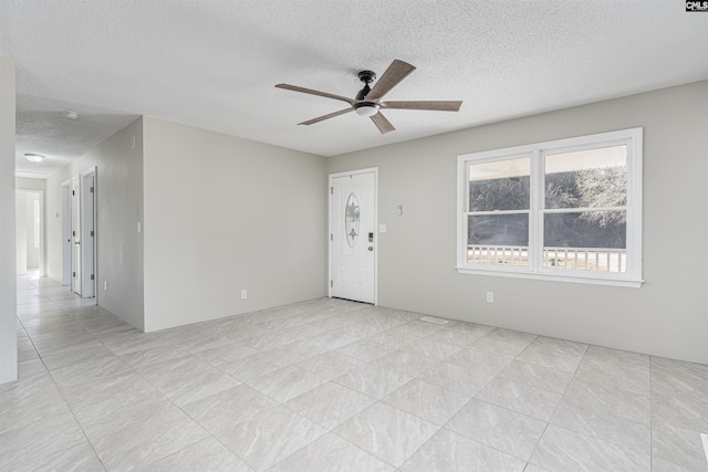 empty room featuring a textured ceiling and ceiling fan