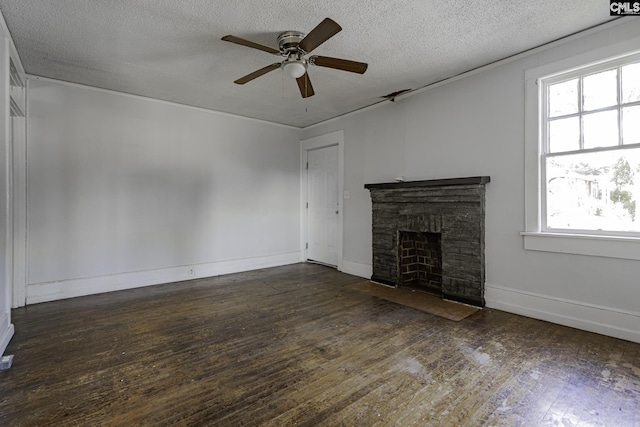 unfurnished living room featuring plenty of natural light, dark hardwood / wood-style floors, a stone fireplace, and ceiling fan