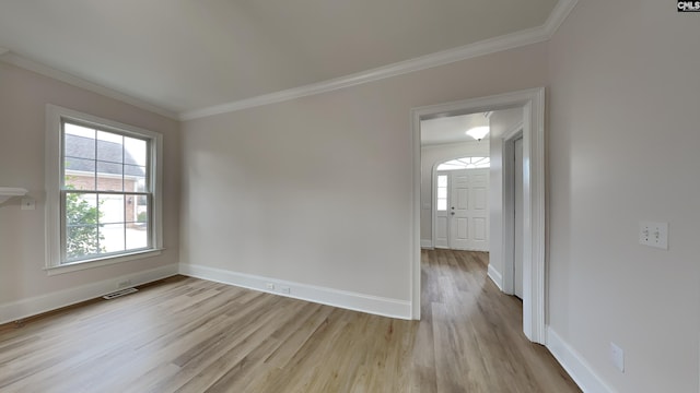 empty room with ornamental molding and light wood-type flooring