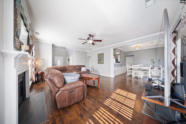 living room with dark wood-type flooring, ornamental molding, and ceiling fan