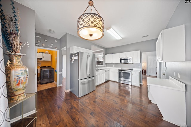 kitchen featuring pendant lighting, sink, white cabinetry, stainless steel appliances, and washer / dryer