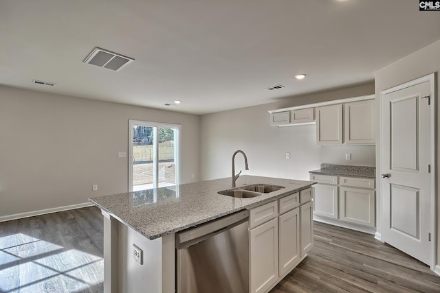 kitchen featuring sink, dishwasher, white cabinetry, light stone counters, and an island with sink