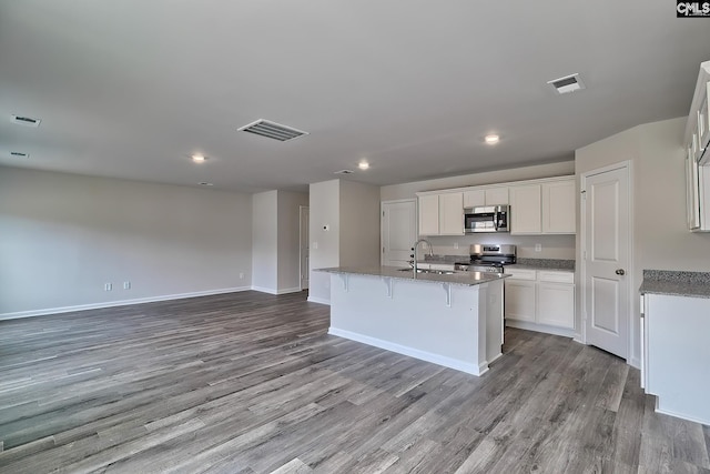 kitchen featuring appliances with stainless steel finishes, white cabinetry, an island with sink, sink, and light hardwood / wood-style floors