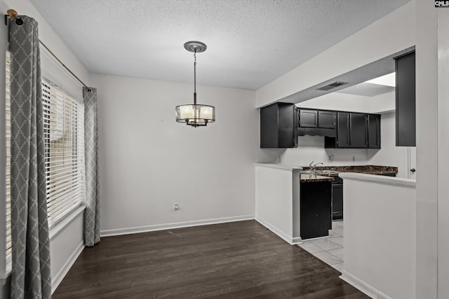 kitchen featuring dark wood-type flooring, sink, a textured ceiling, and decorative light fixtures