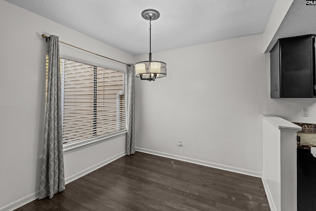 unfurnished dining area featuring dark hardwood / wood-style floors and a textured ceiling