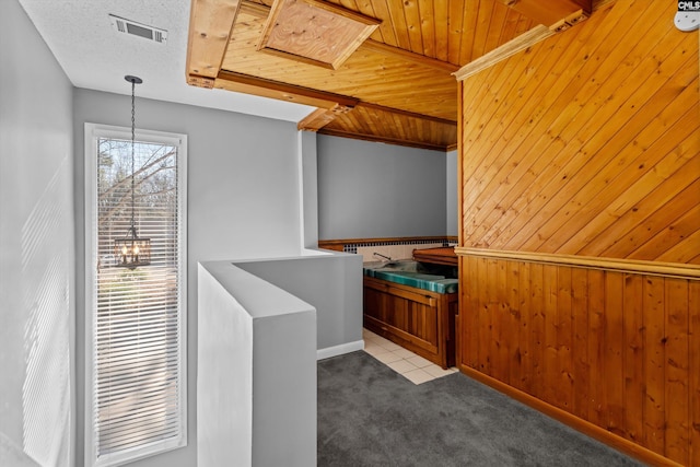 interior space featuring light carpet, wooden ceiling, and wood walls