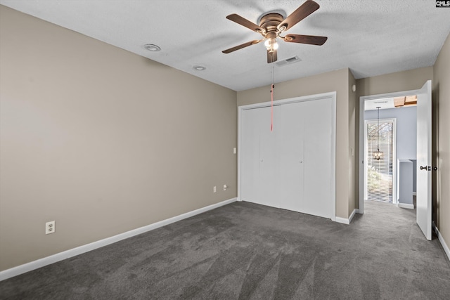 unfurnished bedroom with ceiling fan, dark carpet, a closet, and a textured ceiling