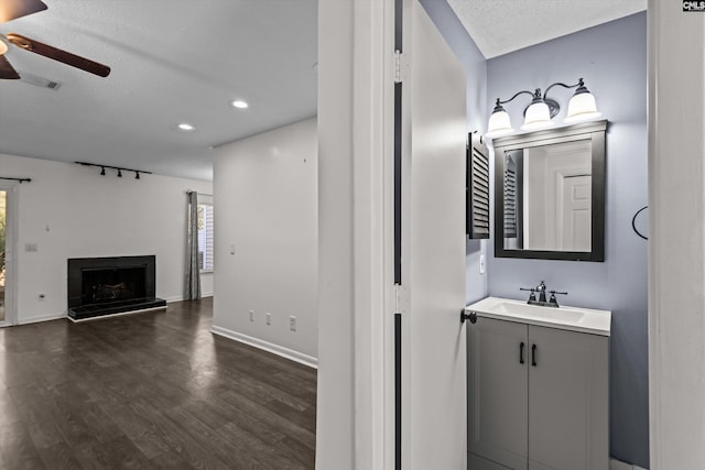 bathroom featuring ceiling fan, vanity, wood-type flooring, and a textured ceiling