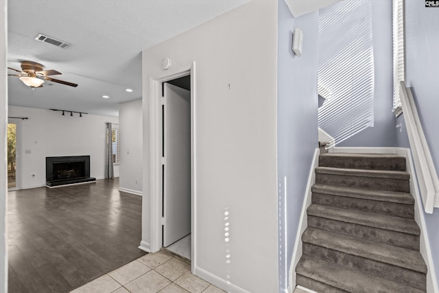 stairs with ceiling fan, tile patterned floors, and a textured ceiling