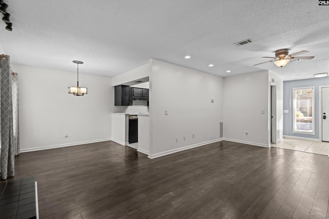 unfurnished living room with a textured ceiling, dark wood-type flooring, and ceiling fan