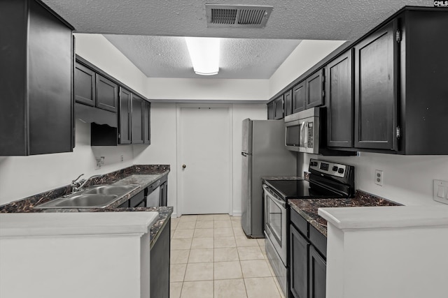 kitchen featuring light tile patterned flooring, stainless steel appliances, sink, and a textured ceiling