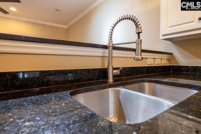 room details with sink, crown molding, ceiling fan, white cabinets, and dark stone counters