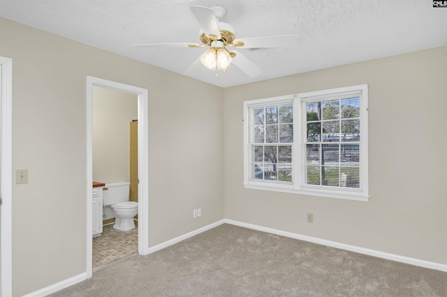 unfurnished bedroom featuring light carpet, connected bathroom, and ceiling fan