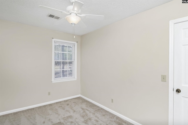 spare room featuring a textured ceiling, light colored carpet, and ceiling fan