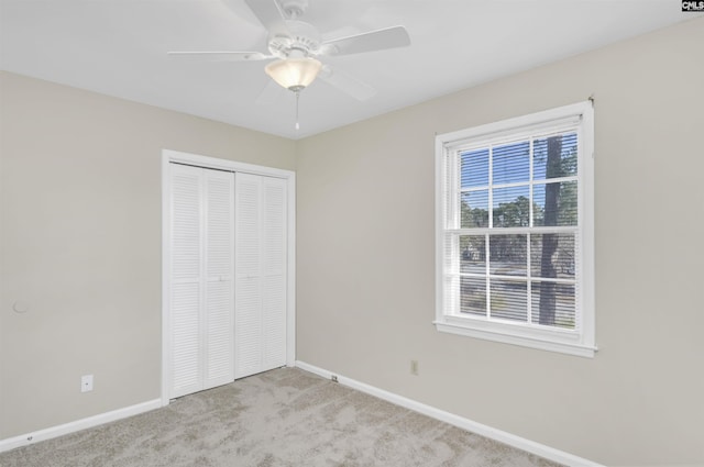 unfurnished bedroom with ceiling fan, light colored carpet, and a closet