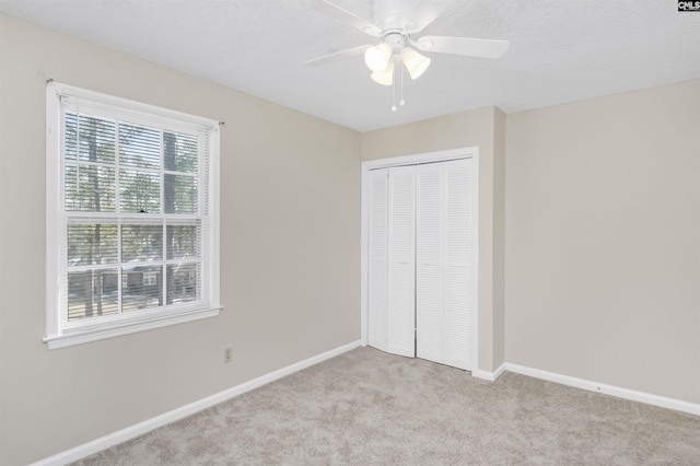 unfurnished bedroom with light carpet, ceiling fan, and a closet